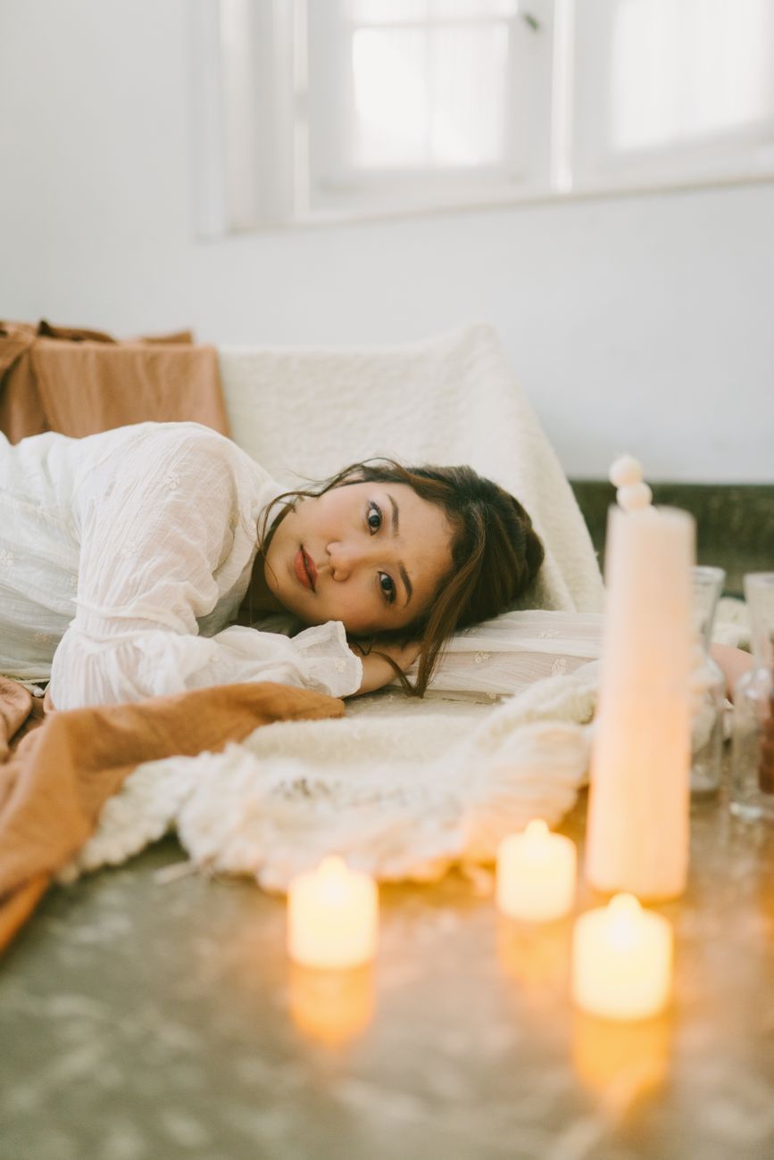 Person resting on a massage table beside candles
