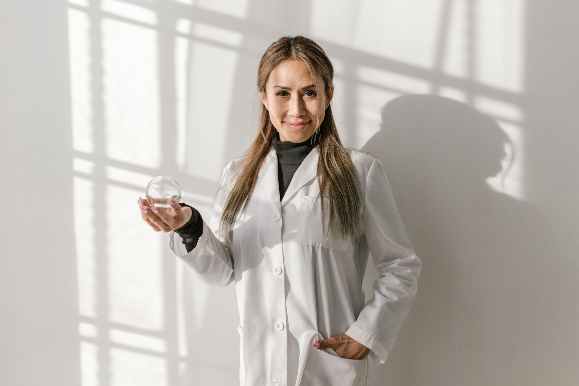 Person in a white coat holding a glass